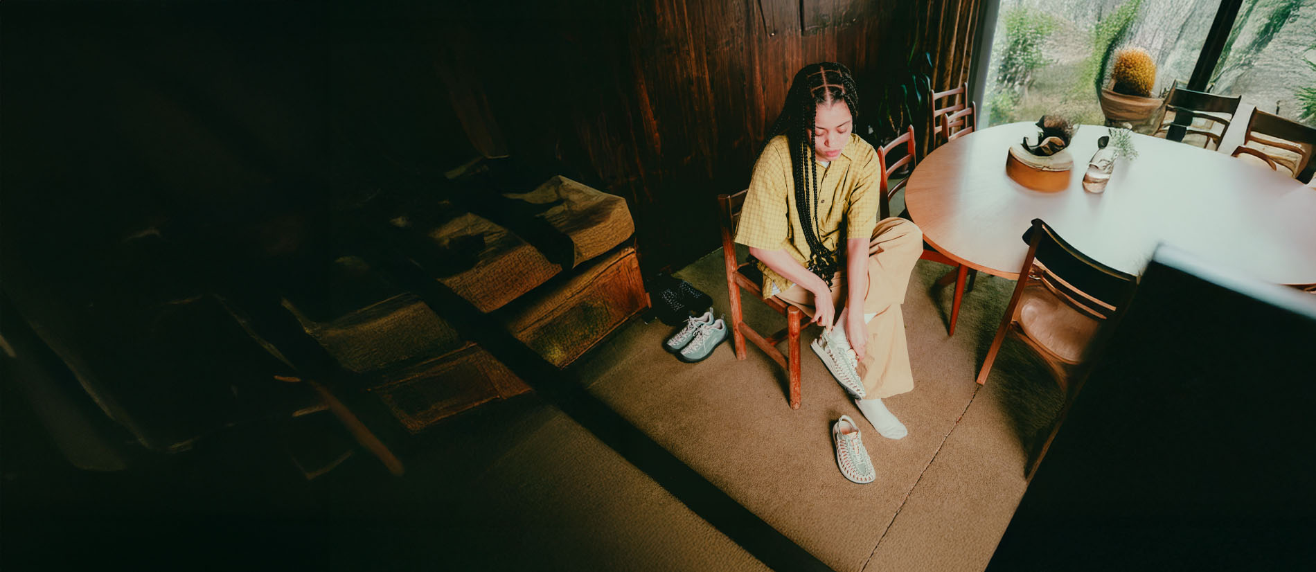 Persona seduta in casa indossa scarpe KEEN lifestyle, utilizzo quotidiano tra casa e città