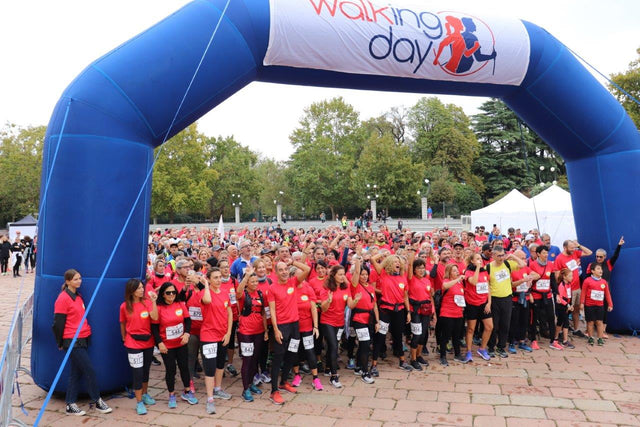 Gruppo di persone in maglietta rossa durante il Walking Day 2023 a Milano, evento di camminata all'aperto con arco blu con scritta "Walking Day".