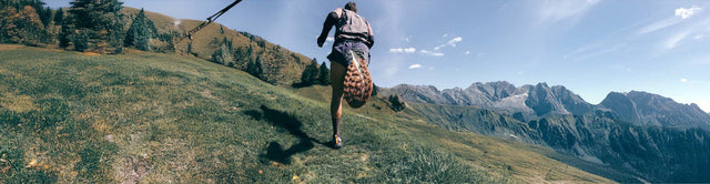 Scarpe trail running KEEN ROAM durante una corsa su terreno roccioso vicino a un torrente, con la suola della scarpa in primo piano.