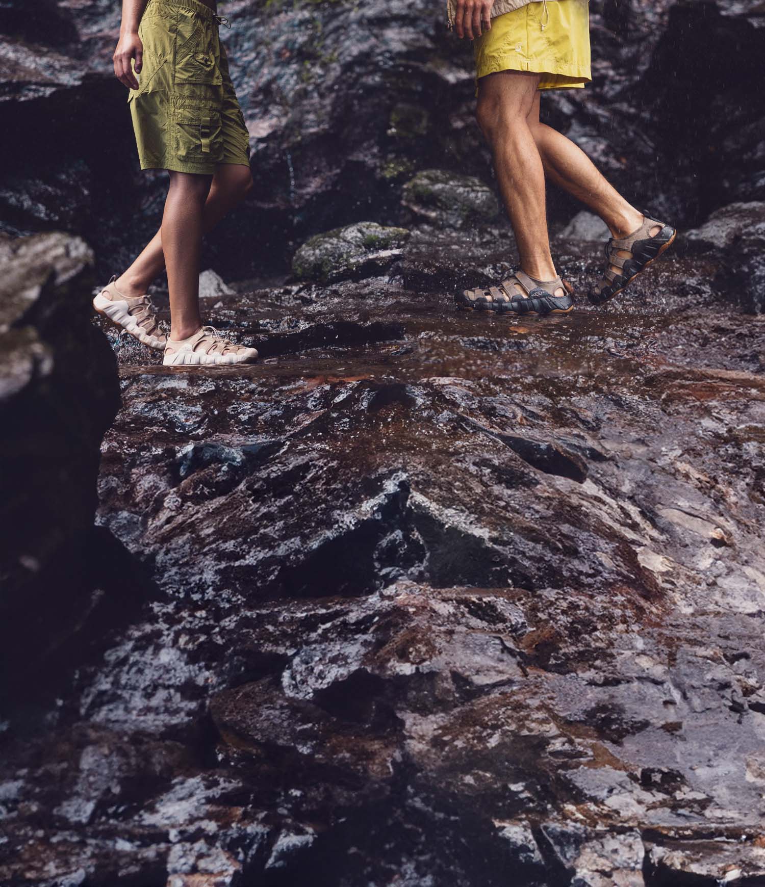 Persone con sandali KEEN su tronco e torrente, ideali per acqua, roccia e uscite outdoor estive