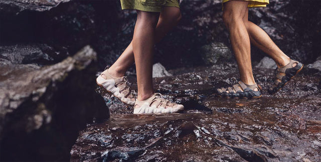 Sandali KEEN Newport e Hyperport indossati su rocce bagnate durante un percorso outdoor vicino all’acqua
