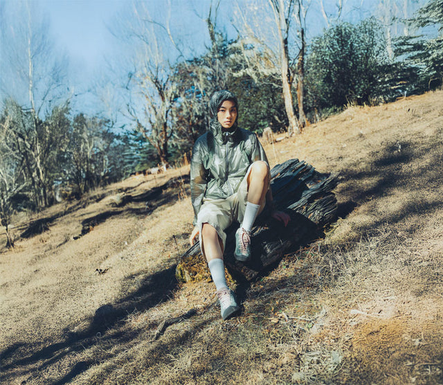 Modella seduta su tronco in ambiente naturale con KEEN Jasper Zionic ai piedi, stile outdoor e tempo libero