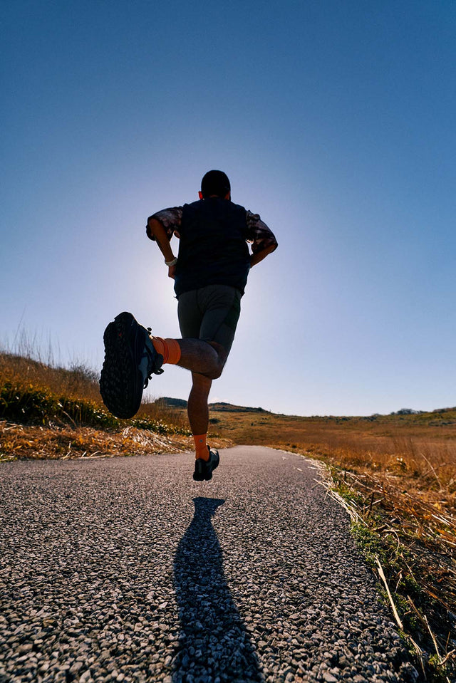 Runner con scarpe KEEN ROAM uomo durante una corsa su strada in un contesto outdoor.