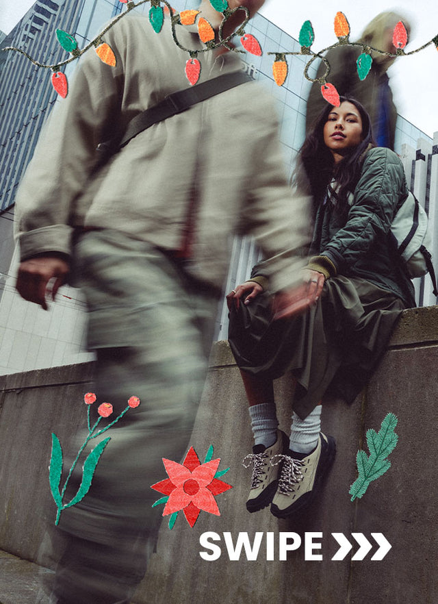 Donna seduta in città con scarponcini KEEN beige e dettagli neri, decorazioni natalizie illustrate intorno.